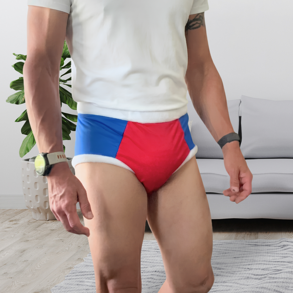 A man wearing red, blue, and white color-blocked adult cloth diaper, paired with a white t-shirt, standing in a living room setting.