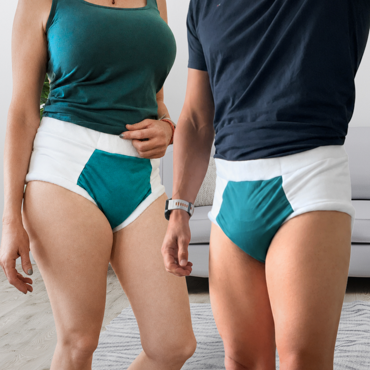 Two models wearing matching teal and white incontinence cloth diapers in a bright indoor setting.